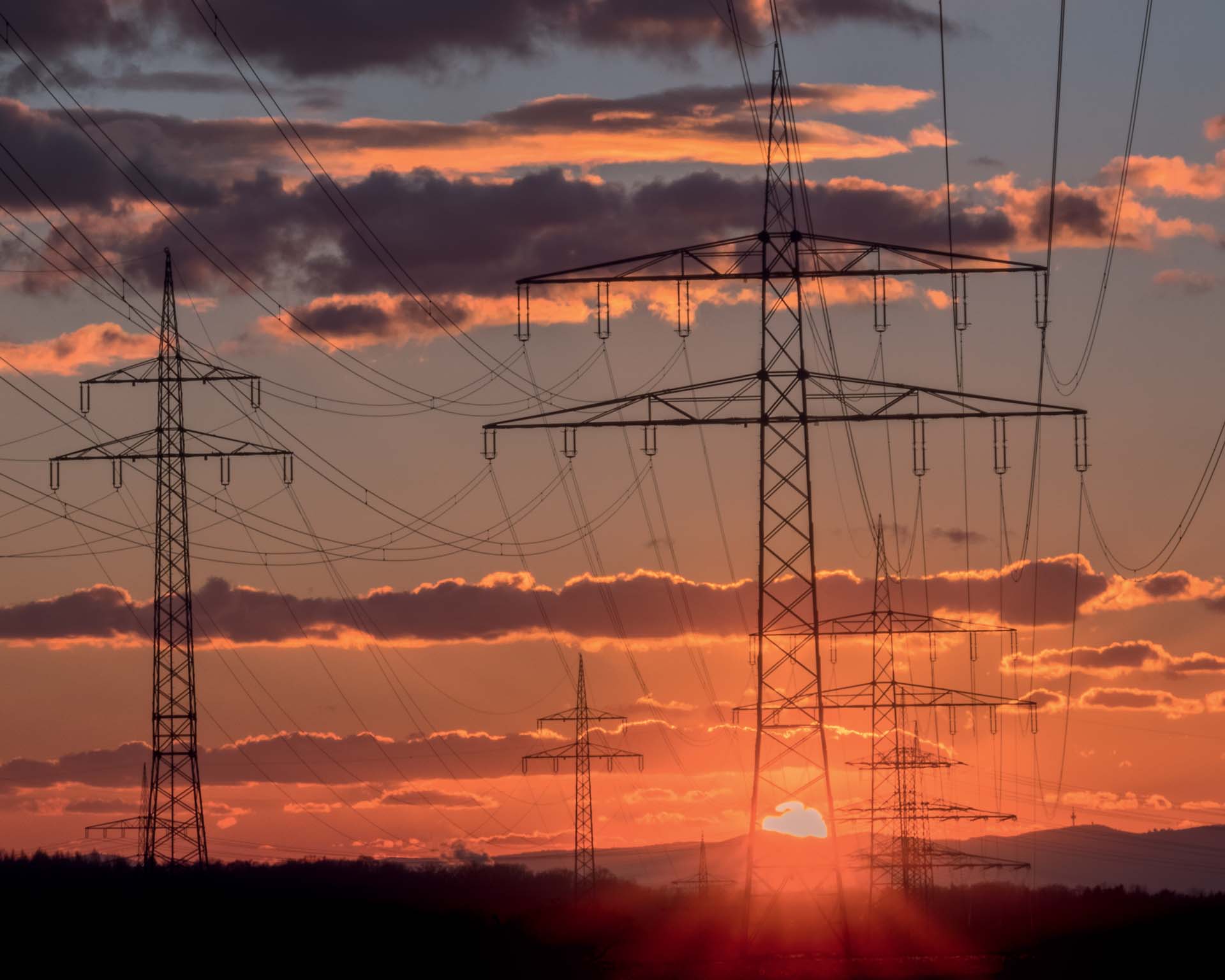 Hochspannungsmasten vor aufgehender Sonne